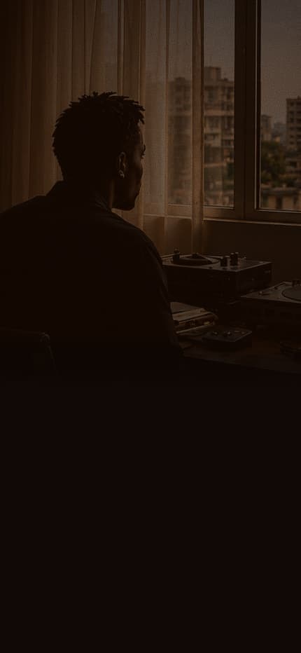 An artist at a turntable setup by a window at dusk